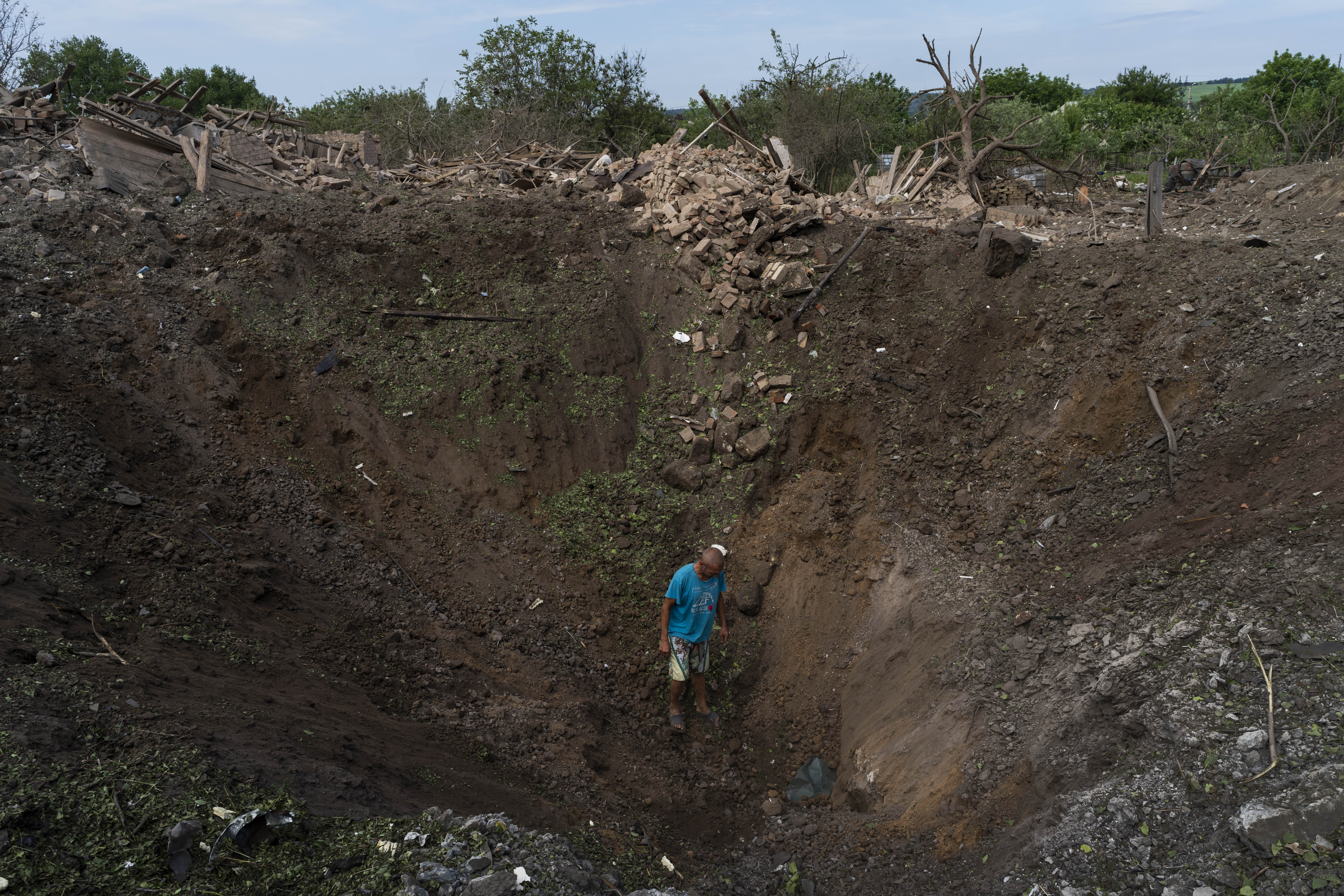 A resident walks into a crater caused by a missile strike in Druzhkivka, eastern Ukraine, Sunday, June 5, 2022. (AP Photo/Bernat Armangue)