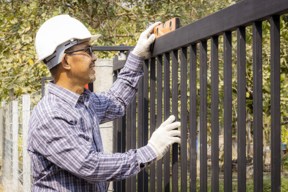 Close-up of half a technician installing a metal door on a very sunny day.